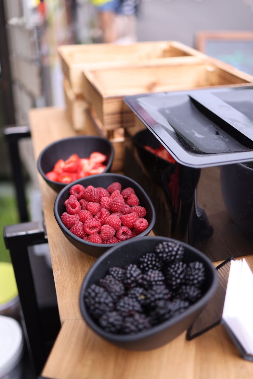 A vibrant display of blackberries and raspberries in bowls on a rustic wooden table.